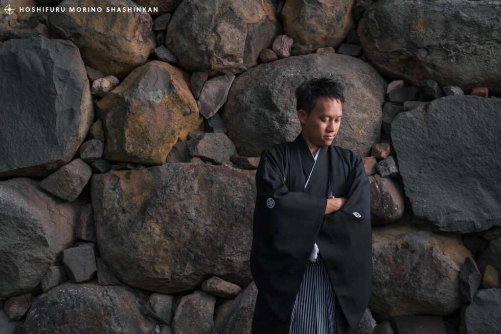 松江城の石垣を背景に立つ新郎