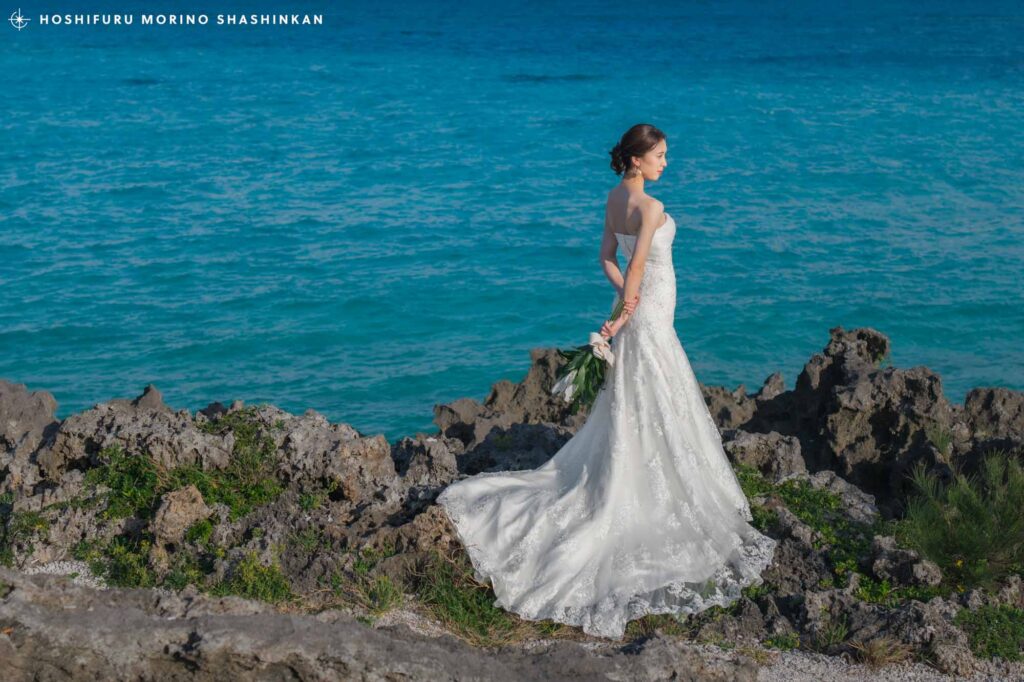 与論ブルーを背景に立つウェディングドレスを着た花嫁